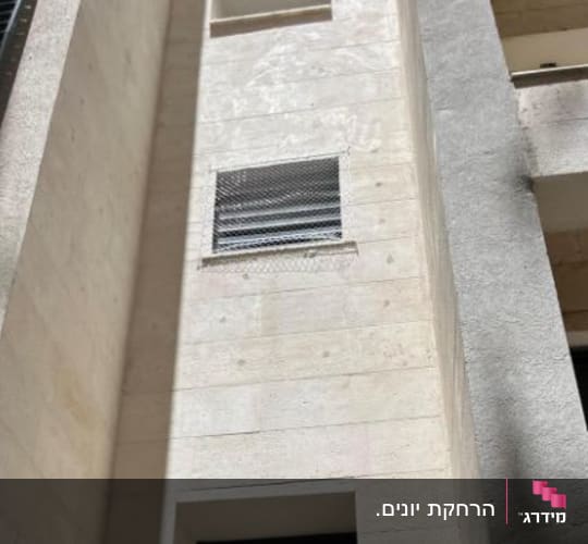 רשת מתכת מותקנת על חלון למניעת כניסת יונים